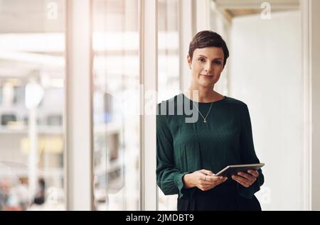 La technologie est le meilleur ami des femmes d'affaires. Portrait court d'une jeune femme d'affaires attirante utilisant sa tablette au bureau. Banque D'Images