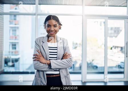 Confiante, fière et professionnelle, jeune femme d'affaires noire repliant ses bras et souriant dans un bureau moderne. Portrait du dirigeant afro-américain Banque D'Images