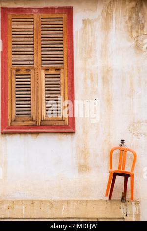 Chaise orange accrochée au mur et belle fenêtre en bois d'une maison traditionnelle dans la vieille ville de Nicosie, Chypre Banque D'Images