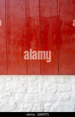 Gros plan sur le mur extérieur vertical en bois rouge vif et en pierre blanchie à la chaux. Banque D'Images