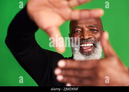 Mettez ce sourire là pour que les gens tombent amoureux. Studio photo d'un homme âgé formant un cadre de doigt devant son visage. Banque D'Images