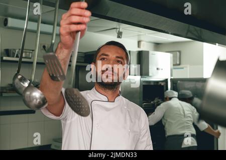 Chef cuisant un plat savoureux dans la cuisine du restaurant en utilisant l'équipement moderne Banque D'Images