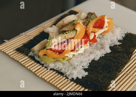 Processus de préparation des futomaki à sushis vegan avec concombre au poivre et salade d'avocat Banque D'Images