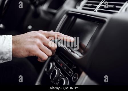 Main du conducteur mâle utilisant l'affichage audio de la voiture Banque D'Images