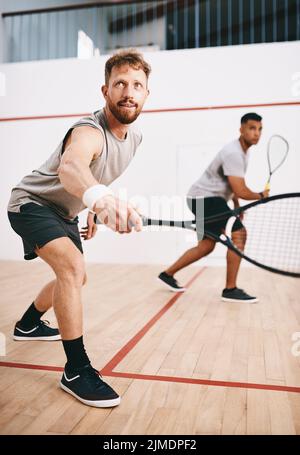 Il n'a que des yeux pour le ballon. Deux jeunes hommes jouent un jeu de squash. Banque D'Images