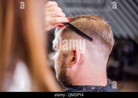 Girl coiffure ciseaux coupe homme barbu dans le salon Banque D'Images