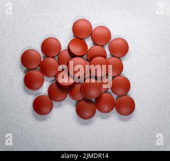 Vue de dessus d'une pile de comprimés d'oxyde de fer rouge de couleur vitamine B12 sur un fond de tissu blanc. Banque D'Images
