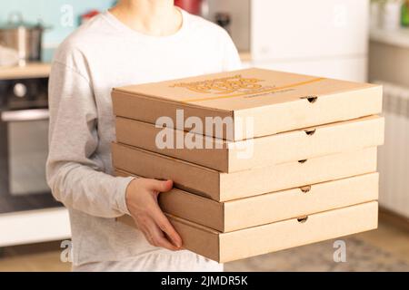 Livraison de nourriture à la maison. Fille tient la commande de pizza ou de tartes sur un fond flou dans la maison Banque D'Images