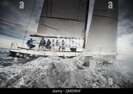 Les participants d'une régate de voile sur le voilier, les cordes de traction, les éclaboussures d'eau au premier plan, se concentrent sur les éclaboussures Banque D'Images