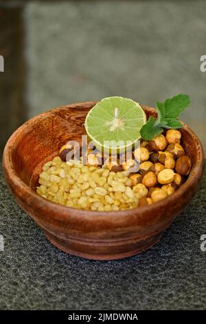 Une dose verticale de grammes jaunes frits, de lentilles en morceaux, d'un citron en tranches et d'une feuille de menthe dans un bol en bois Banque D'Images