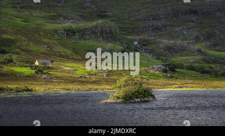 Petite île rocheuse couverte d'arbres torsadés sur le Lough Gummeenduff, anneau du Kerry Banque D'Images
