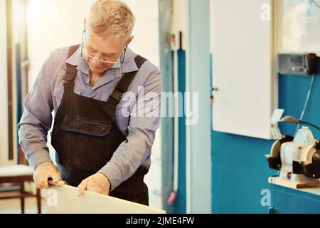 Portrait d'un menuisier âgé ou d'un charpentier travaillant avec des planches en bois dans un atelier de menuisier. Banque D'Images