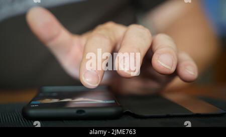 Les doigts d'une personne actionnent un smartphone allongé sur la table Banque D'Images