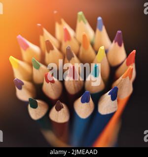 Nouveaux crayons de couleur accentuée sur un fond sombre avec lumière du soleil ou éclairage. Arrière-plan abstrait sur un thème créatif. Banque D'Images