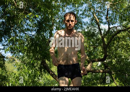 Guy à l'ombre des plantes sans vêtements. Homme en été. Banque D'Images