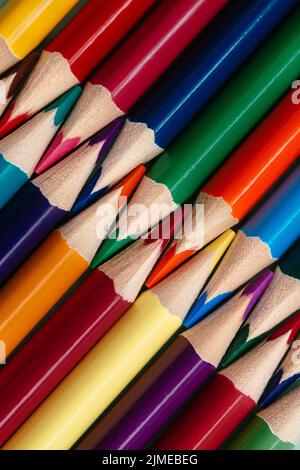 Les crayons de couleur aiguisés se trouvent dans une rangée de gros plan. Arrière-plan abstrait Uni de crayons multicolores en bois. Banque D'Images