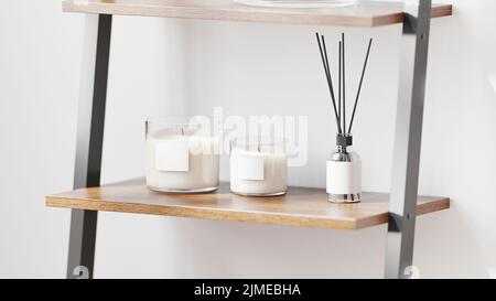 Bougie parfumée en verre avec étiquette vierge maquette avec diffuseur de roseau aromatique sur étagère en bois sur fond de mur blanc, maison aromatique Banque D'Images