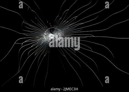 Ligne fissurée sur verre cassé isolée sur fond noir. La texture de l'impact sur le verre. Banque D'Images