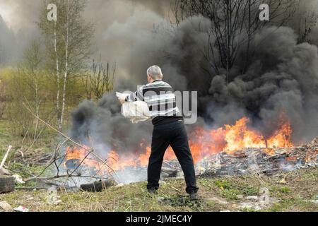 L'homme éteint le feu de lui-même. Homme et feu. Civil lutte contre les flammes. Combustion de déchets dans une décharge illégale. L'activiste combat la fumée. Banque D'Images