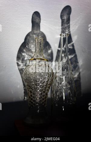 Deux bouteilles millésimes transparentes et une ombre abstraite de celles-ci sur le mur Banque D'Images