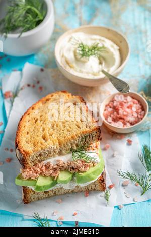 Sandwich maison et savoureux avec avocat, saumon et aneth. Sandwich pour un déjeuner frais. Banque D'Images