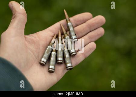 Cartouches dans la paume de votre main. Mitrailleuse de balles dans la main. Coques pour le tournage. Détails des armes militaires. B Banque D'Images