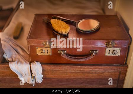 Valise de voyage en cuir vintage sur un lit en bois avec brosse et miroir sur le dessus Banque D'Images