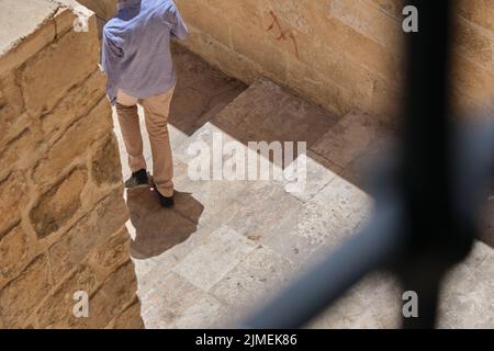 Homme dans une chemise à pantalon blanc et une robe bleue avec un sac à dos dans la rue à Mardin. Vue aérienne d'un touriste. Banque D'Images