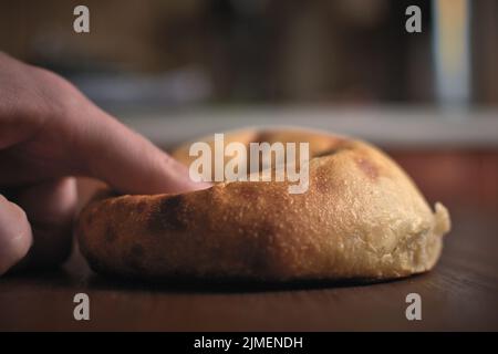 Un hamburger au levain fait maison est pressé avec un doigt. Banque D'Images