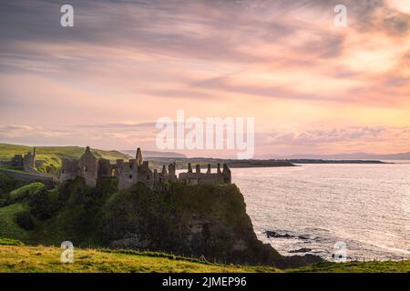 Ciel spectaculaire sur les ruines du château de Dunluce perché au bord de la falaise, Irlande du Nord Banque D'Images