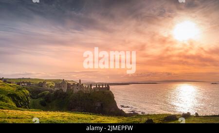 Coucher de soleil sur les ruines du château de Dunluce, perché sur la falaise, Irlande du Nord Banque D'Images