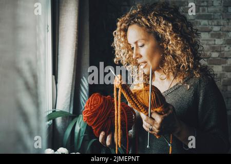 Portrait d'une femme attrayante à la maison dans une activité de loisirs en intérieur utilisant des aiguilles pour tricoter travail laine colorée. Les femmes et les passe-temps. Jeune femme bu Banque D'Images