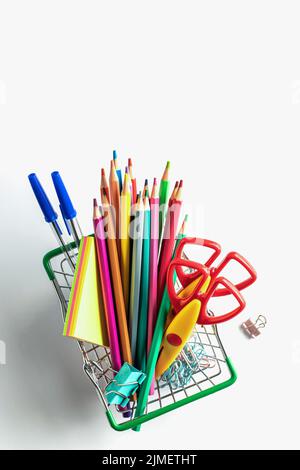 Achat de fournitures scolaires. Panier avec papeterie sur fond blanc isolé, vue de dessus Banque D'Images