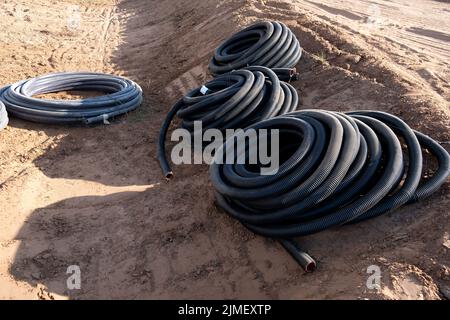 Installations de développement de communications, grande bobine de PVC tuyau noir tube plastique. Tuyaux sur le chantier de construction protéger les câbles dans l'électricité Banque D'Images