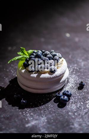 Mini-dessert meringue gâteau pavlova aux myrtilles fraîches sur une table rouillée sombre Banque D'Images