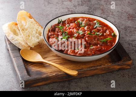 Compotes de poulet dans une sauce tomate épicée gros plan dans un bol sur un plateau en bois sur la table. Horizontal Banque D'Images