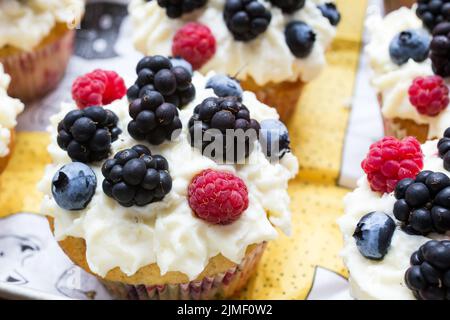 Petits gâteaux faits maison décorés de crème blanche et de baies sauvages, délicieux bonbons frais Banque D'Images