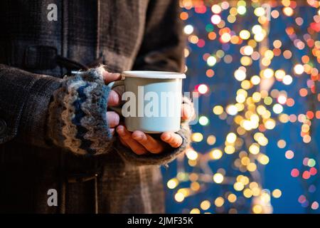 Femme tenant une tasse avec du vin chaud ou du chocolat chaud au marché de noël Banque D'Images