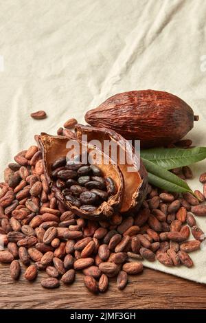 Fèves de cacao non pelées avec des gousses sur le tissu Banque D'Images