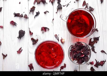 Vue supérieure à deux tasses de thé avec de la glace sèche et pétales d'hibiscus sur fond de table en bois blanc Banque D'Images