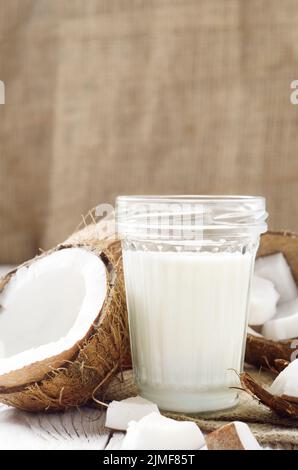 Pot Mason de lait ou de yogourt sur le chanvre serviette sur une table en bois blanc à la noix de coco de côté Banque D'Images