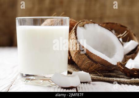 Boire un verre de lait ou de yogourt sur le chanvre serviette sur une table en bois blanc à la noix de coco de côté Banque D'Images