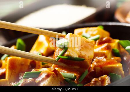 Plat de tofu Mapo de caillé de soja maintenu dans des baguettes Banque D'Images