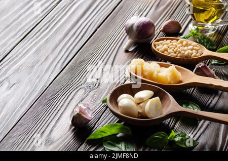 Gros plan sur les cuillères en bois avec des ingrédients alimentaires pour les genovese sauce pesto sur la table de cuisine Banque D'Images