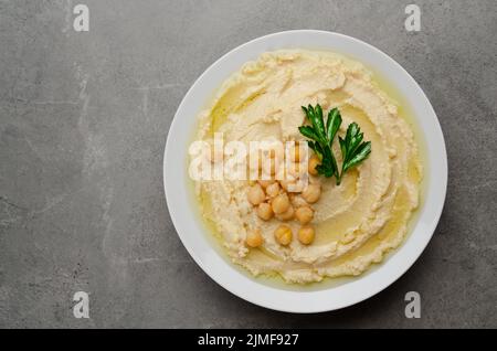 Vue plate sur l'humus surmontée de pois chiches et de feuilles de coriandre verte sur la table en pierre Banque D'Images