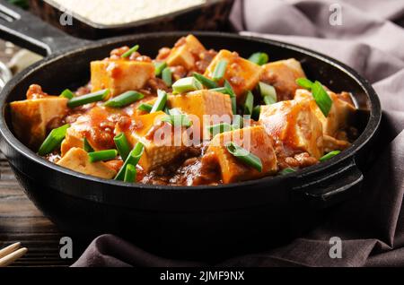 Mapo tofu dans une poêle en fonte avec ciboulette hachée de porc sauce soja poivre du sichuan ail et épices Banque D'Images