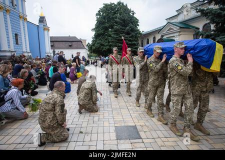 Kiev, Ukraine. 05th août 2022. Les gens s'agenouillent devant le cercueil avec le corps du poète ukrainien Hlib Babich lors de la cérémonie d'adieu près du monastère de la Domed dorée de Saint-Michel à Kiev. Hlib Babich a récemment été tué dans des batailles avec les troupes russes alors que l'attaque de la Russie contre l'Ukraine se poursuit. Crédit : SOPA Images Limited/Alamy Live News Banque D'Images