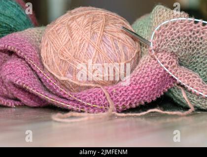 Vêtements tricotés, accessoires dans le processus de création. Aiguilles à tricoter et boule de fil, coloré, jaune, rose, tissu gris, fils de laine de différents Banque D'Images