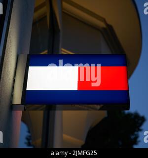 Néon avec le logo du designer de mode Tommy Hilfiger dans une rue commerçante de Berlin Banque D'Images