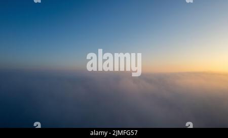 Vue aérienne. Voler dans le brouillard, voler dans la brume au-dessus des nuages tôt le matin dans le soleil levant. Prise de vue aérienne. Vol au-dessus de la cl Banque D'Images